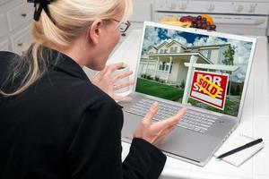 mujer emocionada en la cocina usando una laptop - éxito inmobiliario foto