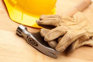 Yellow Hard Hat, Gloves and Hammer on Wood photo