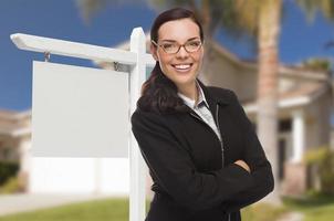 mujer frente a la casa y cartel de bienes raíces en blanco foto