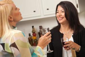 dos amigas disfrutan del vino en la cocina foto