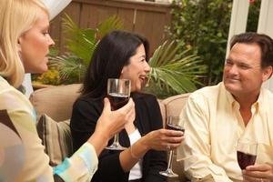 tres amigos disfrutando del vino en el patio foto