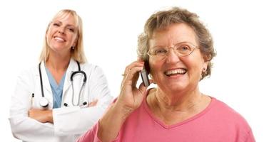 Happy Senior Woman Using Cell Phone with Female Doctor Behind photo