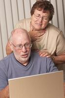 sonriente pareja de adultos mayores divirtiéndose en la computadora foto