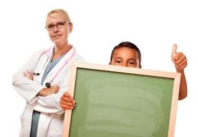 doctora con niño hispano sosteniendo pizarra foto