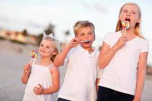 Cute Brother and Sisters Enjoying Their Lollipops Outside photo