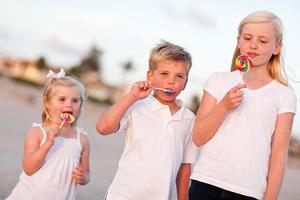 Cute Brother and Sisters Enjoying Their Lollipops Outside photo