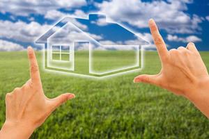 Female Hands Framing House Over Grass and Sky photo