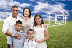 familia hispana de pie en un campo de hierba con una casa fantasma detrás foto
