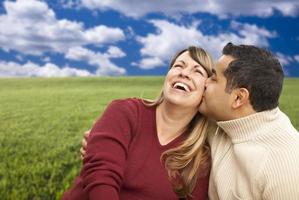 Happy Mixed Couple Sitting in Grass Field photo