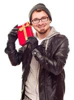 Warmly Dressed Young Man Holding Wrapped Gift To His Ear photo