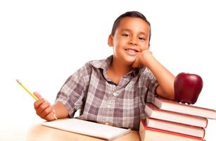 adorable niño hispano con libros, manzana, lápiz y papel foto