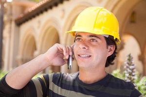 Handsome Hispanic Contractor on Phone with Hard Hat Outside photo