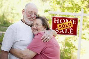 Senior Couple in Front of Sold Real Estate Sign photo