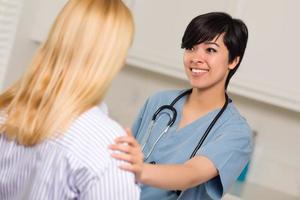 atractiva joven doctora multiétnica hablando con el paciente foto