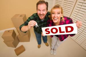 Goofy Couple Holding Key and Sold Sign Surrounded by Boxes photo