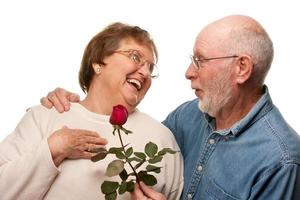 feliz marido mayor dando rosa roja a su esposa foto