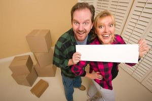 Happy Couple Holding Blank Sign in Room with Packed Boxes photo