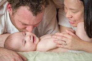 Mixed Race Chinese and Caucasian Baby Boy Laying In Bed with His Parents photo