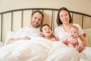 Mixed Race Chinese and Caucasian Baby Boys Laying In Bed with Their Father and Mother photo