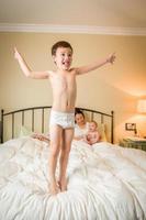 Mixed Race Chinese and Caucasian Boy Jumping In Bed with His Family photo