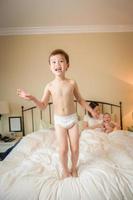 Mixed Race Chinese and Caucasian Boy Jumping In Bed with His Family photo