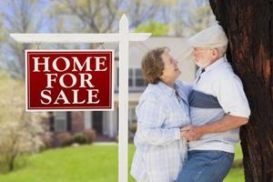 Happy Senior Couple Front of For Sale Sign and House photo