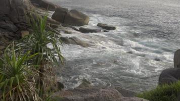 Luftaufnahme von oben auf einer tropischen Insel und Meereswellen, die gegen einen felsigen Strand krachen und schäumen. tourismuskonzept nach covid video