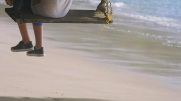 persona oscillante su un' paradisiaco spiaggia sotto palma alberi. bianca sabbioso spiaggia e blu turchese incontaminato acque rendere su un eccezionale vacanza video