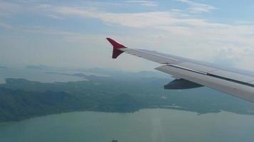 visie van de venster Bij passagier stoel in vliegtuig vlucht bovenstaand wolken en zee met tropisch eilanden video