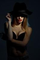 young girl in black bra with red lips wearing a hat with wide brim in studio photo