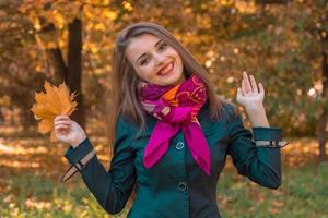 una joven alegre se para en el otoño en la calle y levantó las manos foto