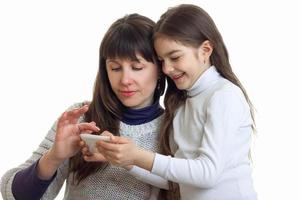 Young adult mother with her daughter using a mobile phone in studio photo