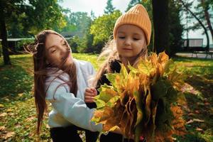 madre con hija recoge un ramo de hojas de otoño en el parque foto