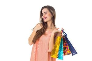 cute young girl looks away smiling and holding a colored bags isolated on white background photo