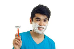 the charming, smiling guy with foam on his face smiling and holding a shaving machine photo