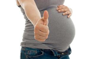 the midsection of a young pregnant woman who raised her hand forward and shows a close-up of a class is isolated on a white background photo