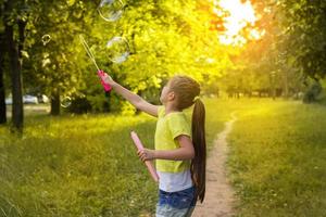 happy little girl having fun with soap bubbles photo