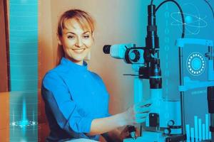 Happy young beautiful Doctor at work machine for checking vision photo