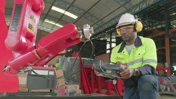 An African American production engineer test and control robotic arm in mechanical manufacturing factory, intelligent automatic machines in industrial business, and futuristic technology innovation. video