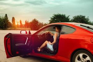 lady with red lips sits in red sport car photo