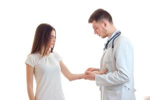 a young doctor in a dressing gown makes a prick of a girl's hand photo