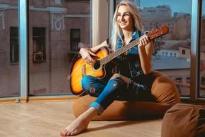 encantadora chica sonriendo y divirtiéndose tocando la guitarra foto