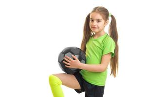 niña con colas en camiseta verde sosteniendo una pelota foto