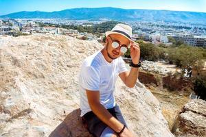 young stylish guy on top of a mountain overlooking the city photo