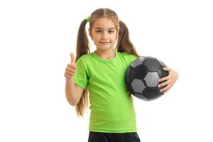 little girl with soccer ball in hands looking at the camera showing thumbs up photo