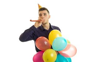 un joven alegre con un cono en la cabeza se mantiene cerca de la boca dudelku y muchos globos aerostáticos de colores foto