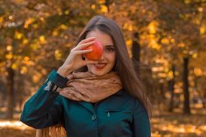 linda chica sosteniendo la manzana de la mano cerca de una persona en el parque foto