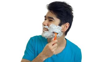 young gay guy turned his head to the side and shaves his beard with foam