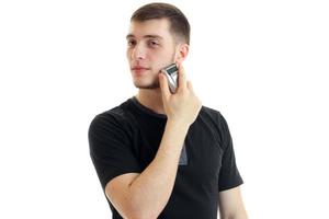 young charming guy turned his head to the side and shaves a beard trimmer photo