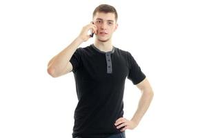 a young guy in a black t-shirt is calling on a cell phone photo
